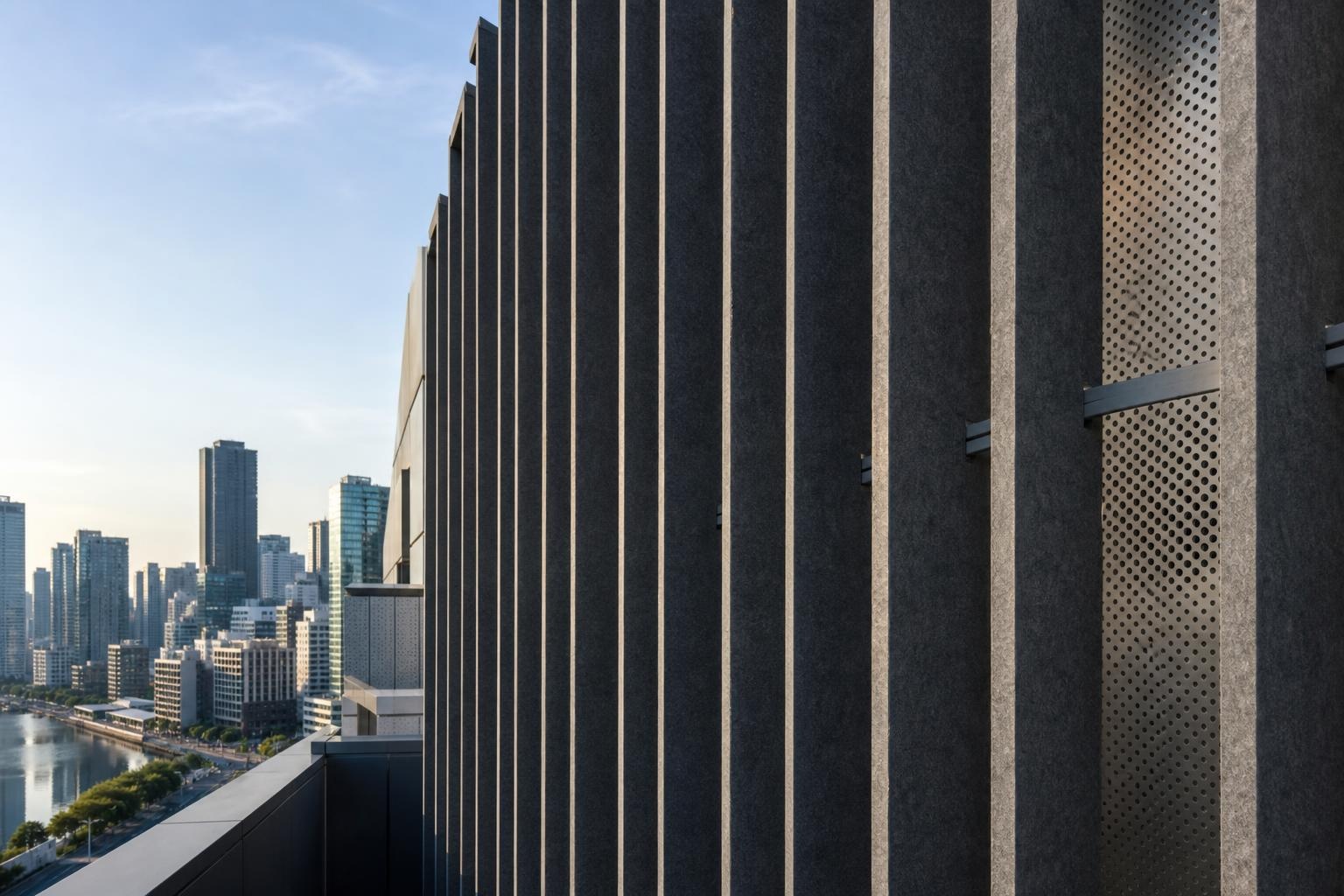 Illustrative rooftop facade with vertical acoustic fins and perforated panels above an anonymous city skyline.