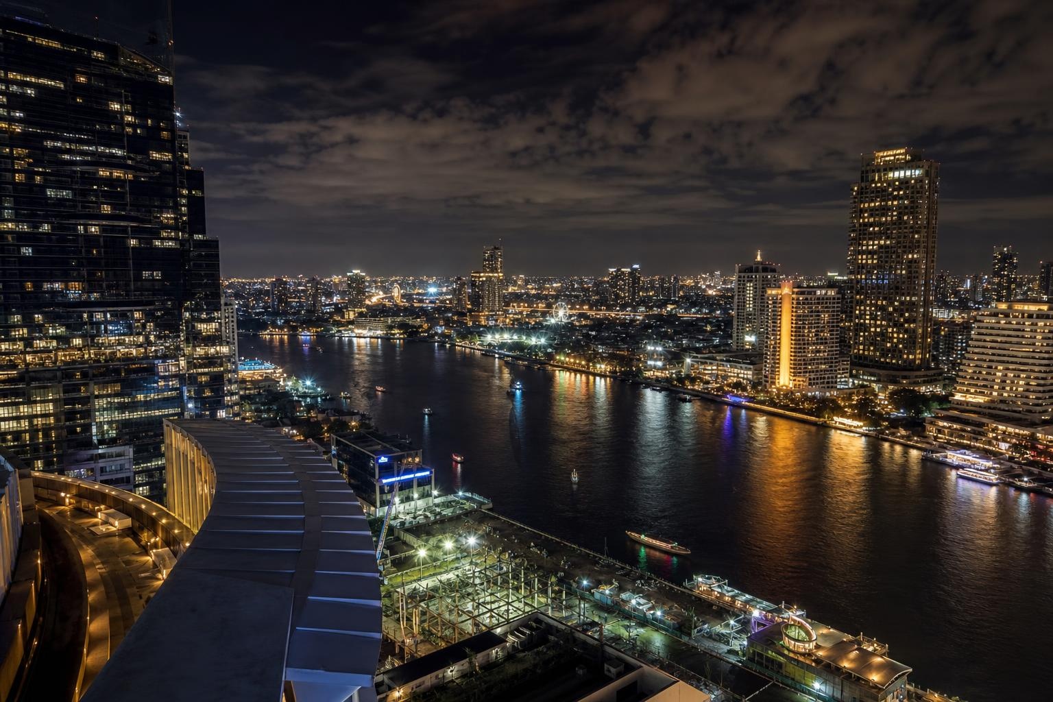 Illustrative nighttime skyline of a dense Asian city beside a river.
