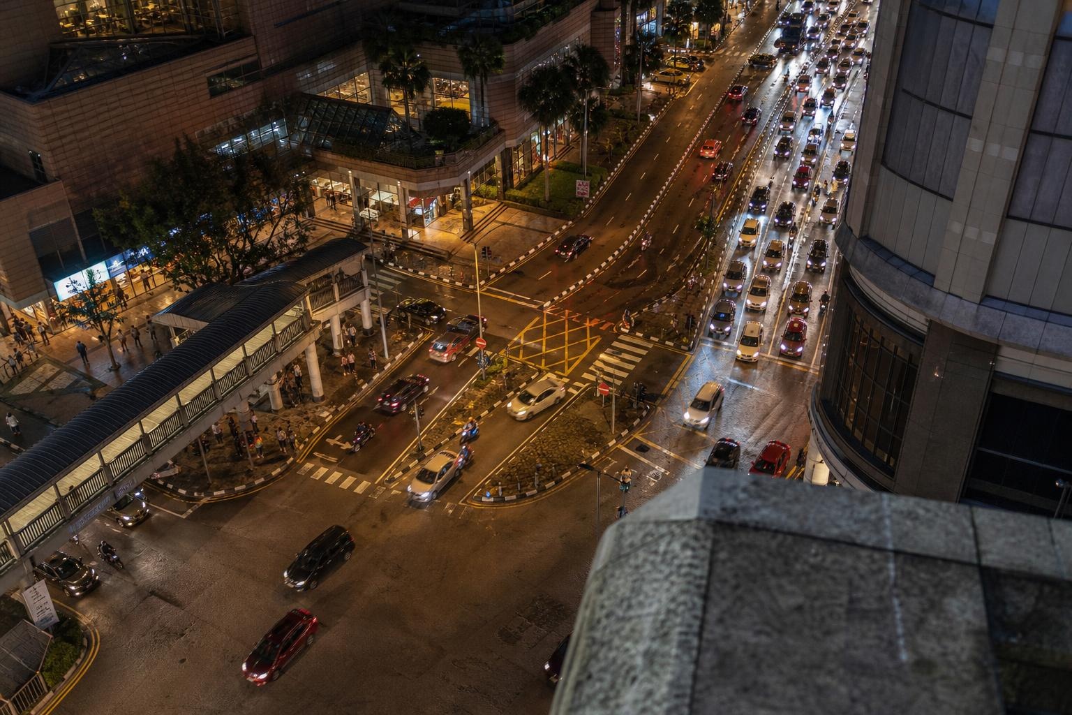 Illustrative elevated view of wet nighttime traffic in a dense Asian city.