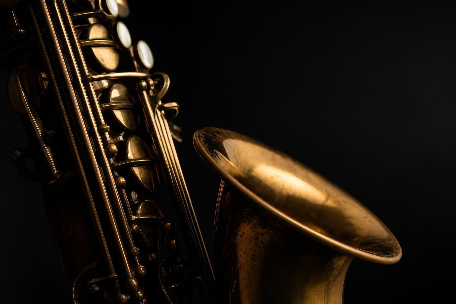 Illustrative close-up of polished brass saxophone keys against a dark neutral background.